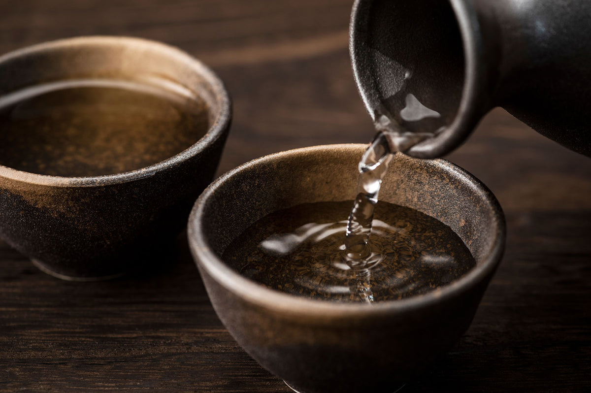 Japanese sake being poured into traditional ceramic cups